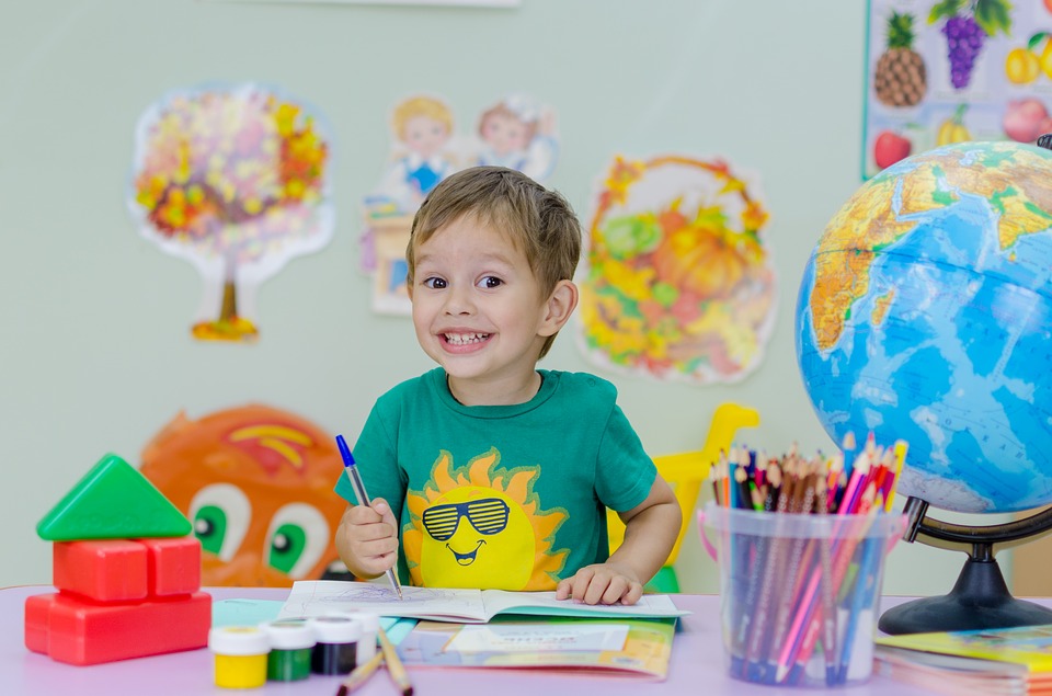 young child between 6 and 8 years old coloring at the table of a school daycare center