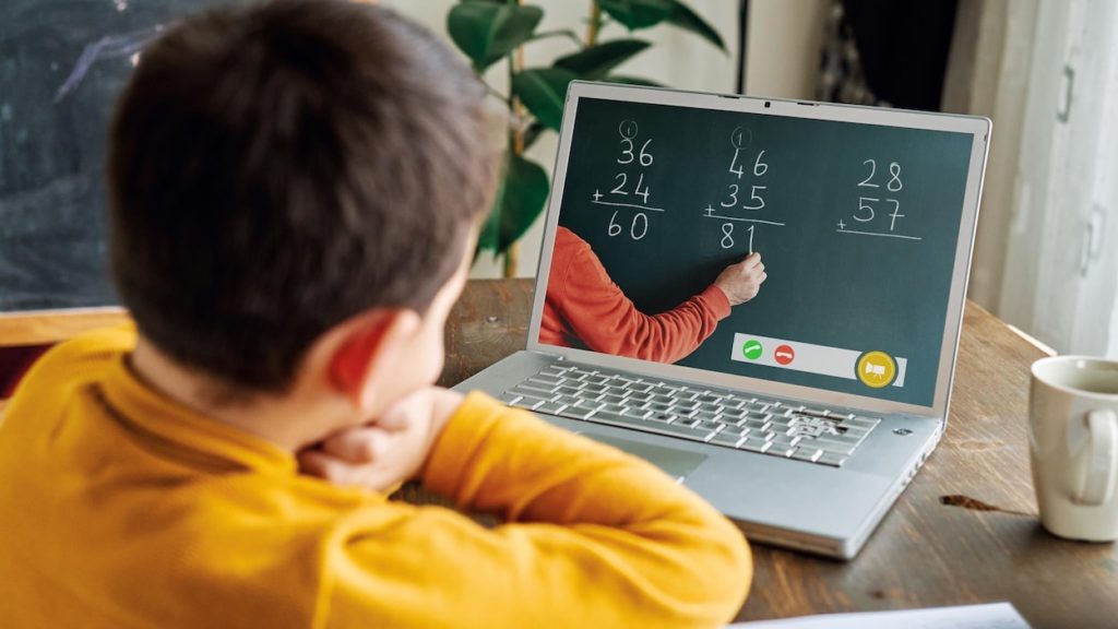 Child watching a calculation video (with chalk and blackboard) on a laptop at home