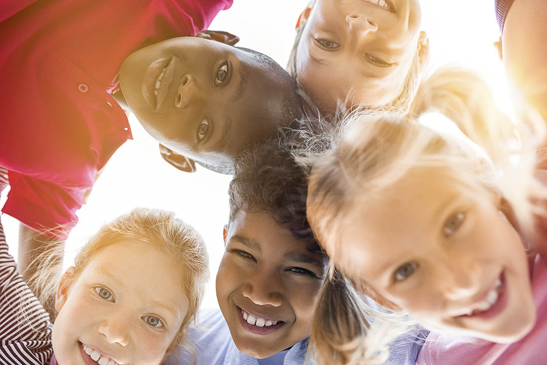 Cinq enfants en train de sourire à une caméra