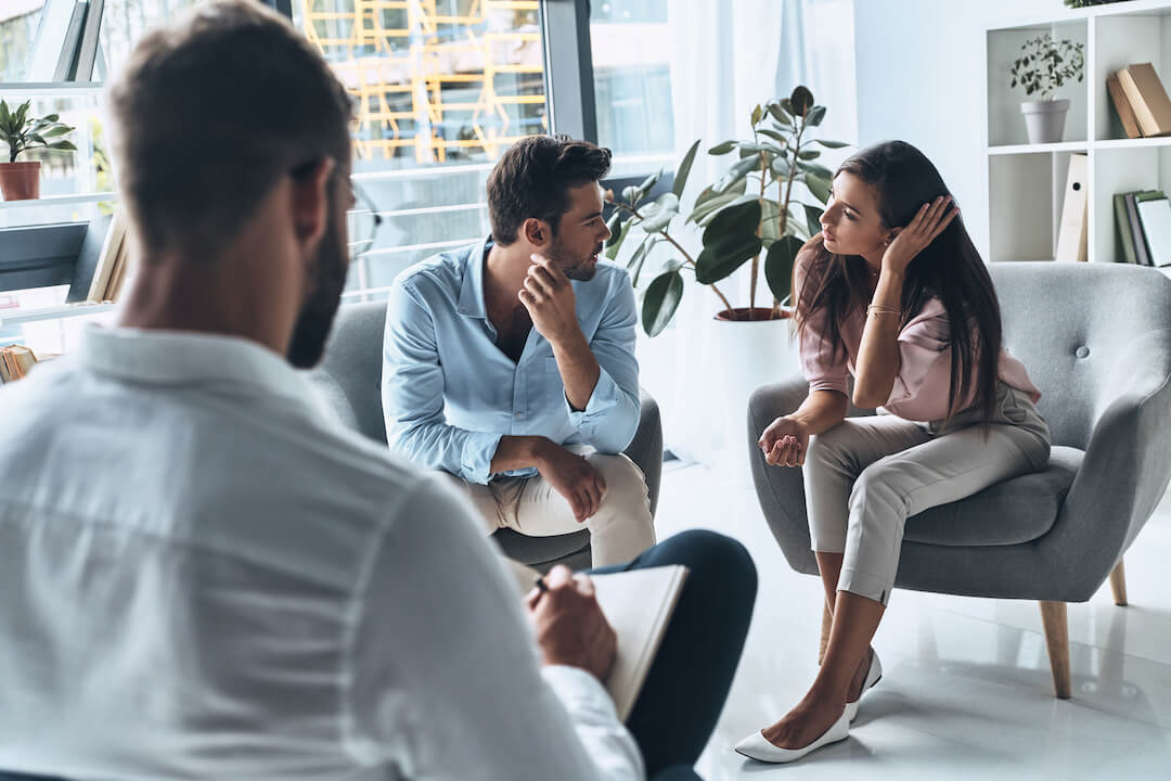 Couple argues in therapy session as psychologist analyzes their situation