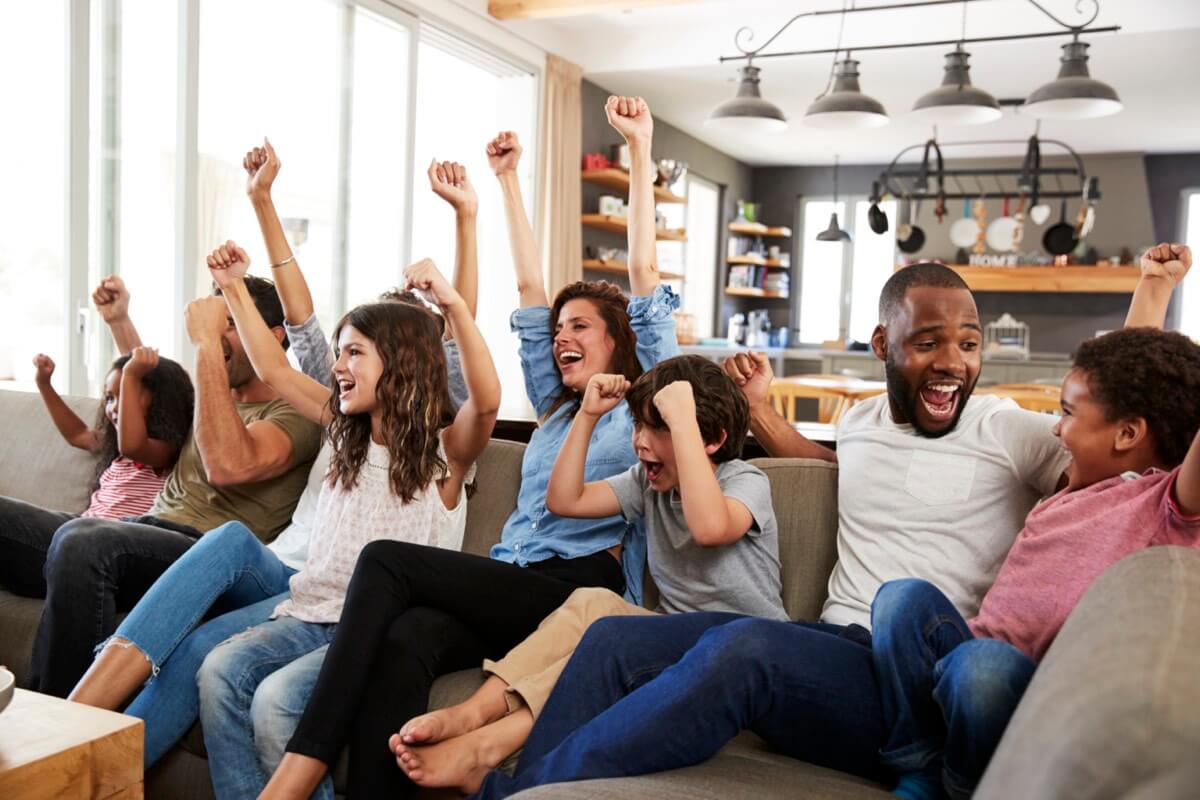 Une famille réunie regardant les sports à la télévision et acclamant