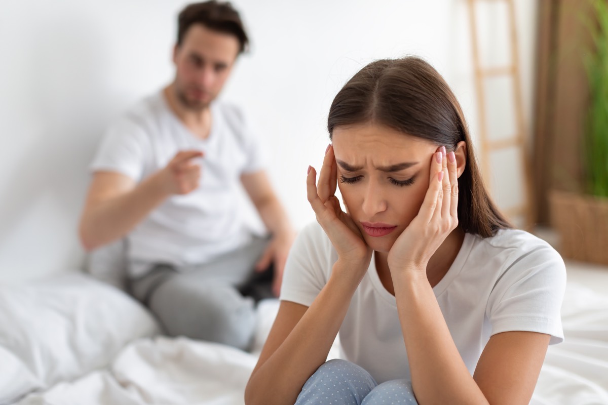 Wife listening to her husband's reproach having quarrel sitting in the bedroom