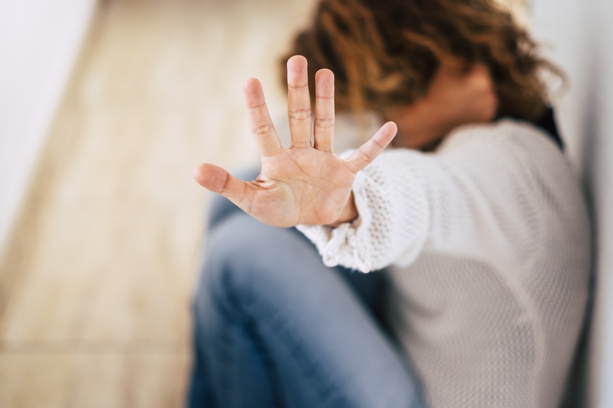 Woman at home showing stop sign to protect herself from physical violence