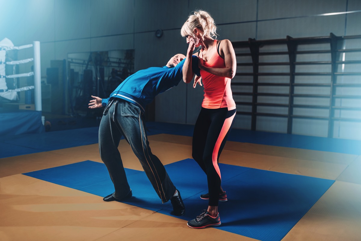 Femme en action sur l'entraînement d'autodéfense avec un instructeur personnel