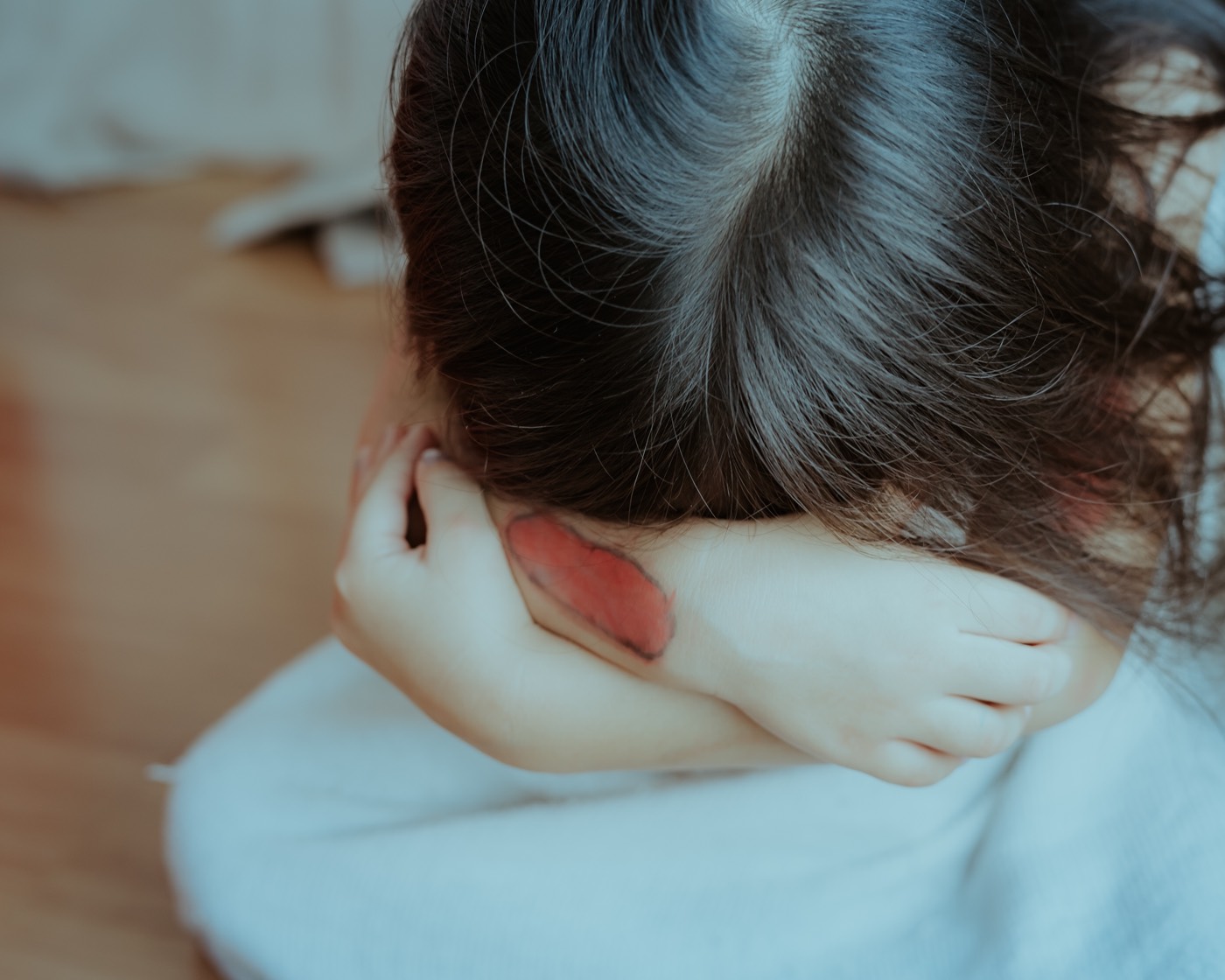 Sad and scared little girl covering her face caused by the abuse she is undergoing