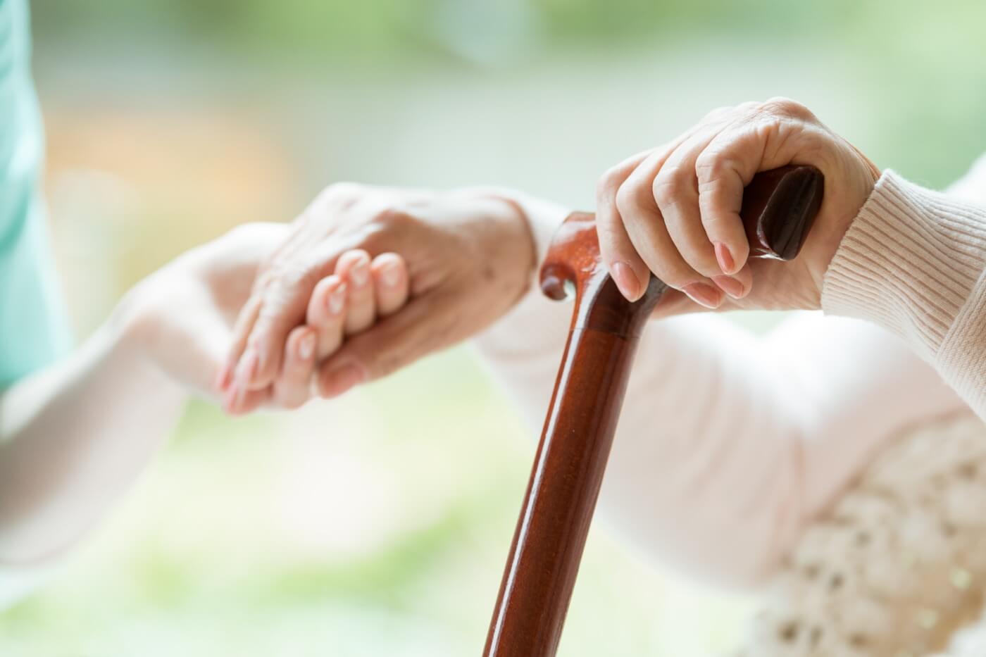 Selective shot of a young person holding the hand of an older person in order to provide support