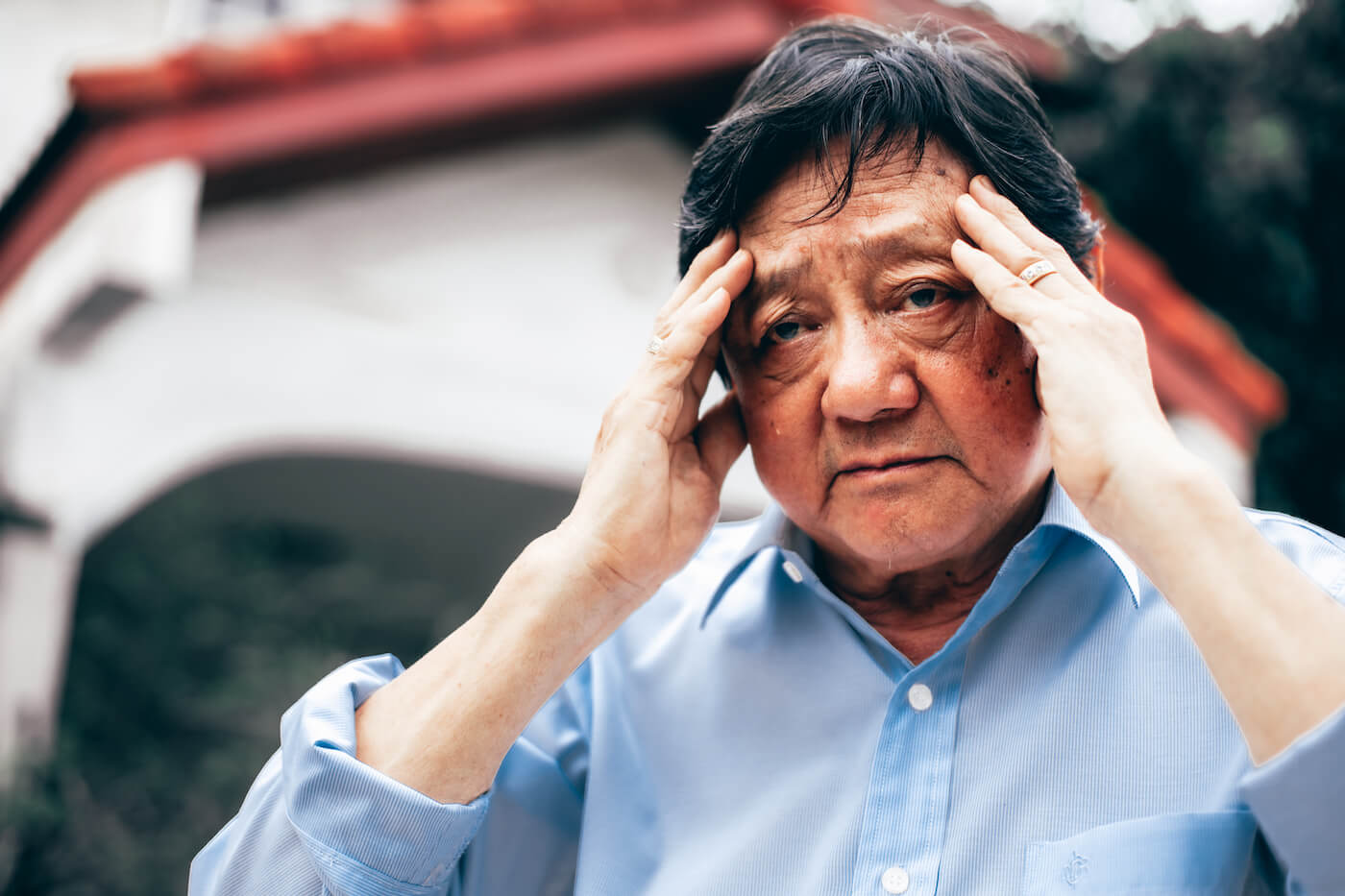 Elderly man holding his head, suffering from psychological problems