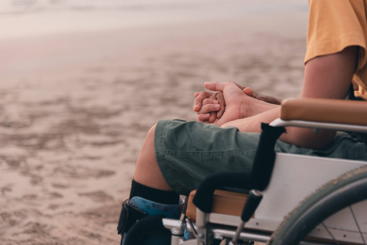 enfant handicapé en fauteuil roulant tient la main de son parent