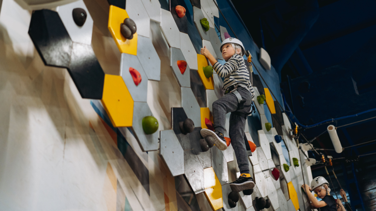 enfant en train de faire de l'escalade sur un mur d'escalade intérieur