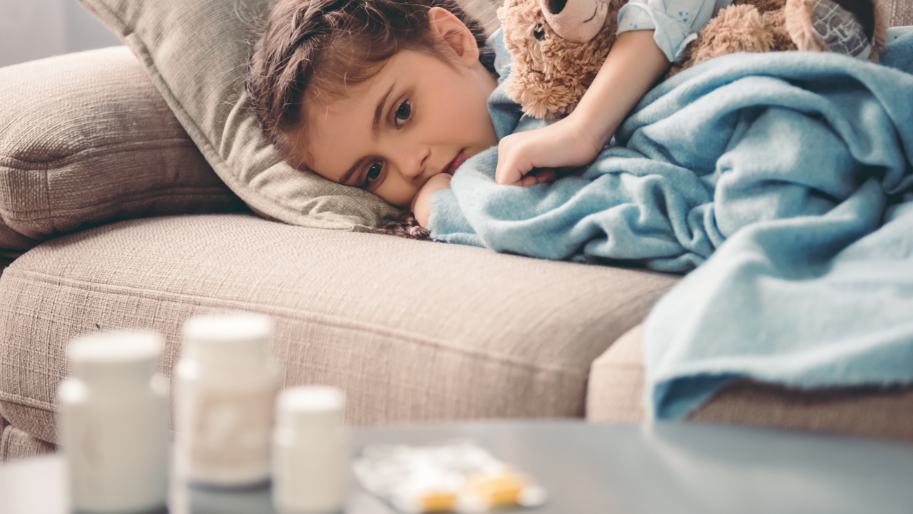 little girl on a couch looking at medecine on a nearby table