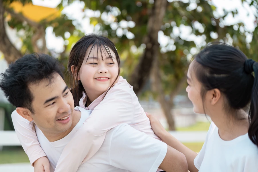 Enfant souriant porté sur le dos d’un adulte, illustrant un moment familial positif et un accompagnement bienveillant.